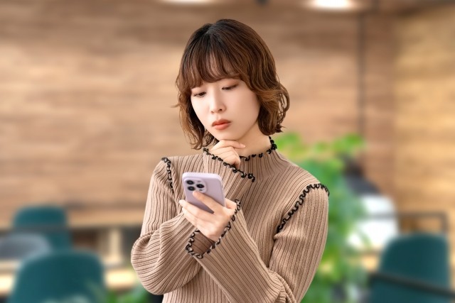 スマホを見て考える女性・ビジネスウーマン