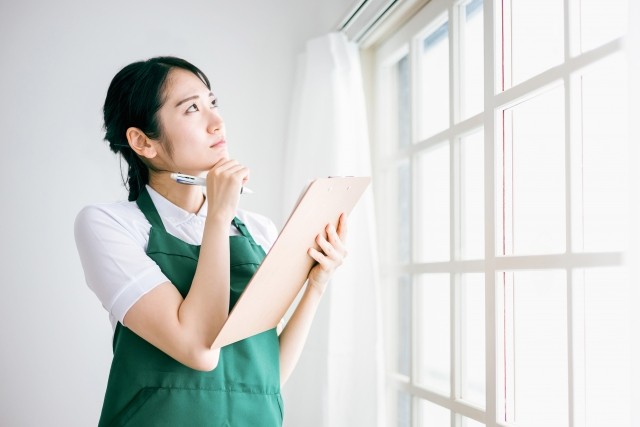 窓・カーテンレールをチェックする女性