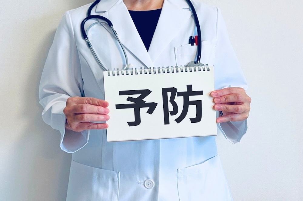 医者の服を着た人が予防と書かれた紙を持っている画像