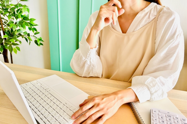 パソコンを見ながら家計を考える主婦