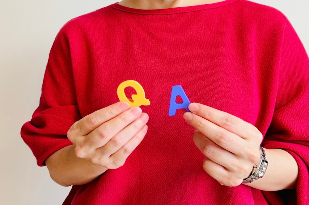 QとAの文字を持った男性の画像