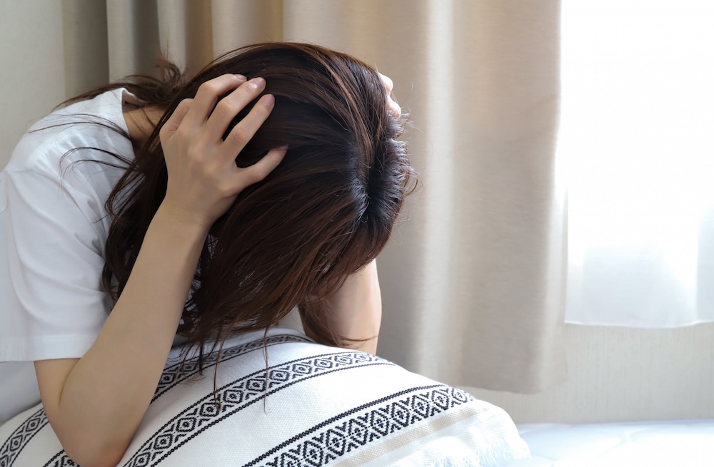 ベッドで頭を抱えている女性