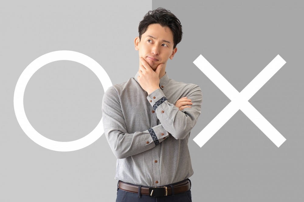 ○と✖️の書かれた真ん中に考える男性