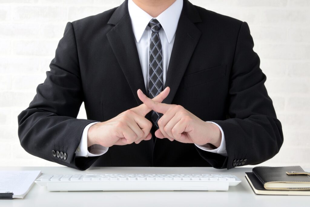 ×を作るスーツの男