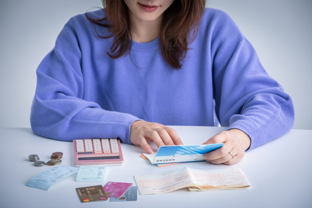電卓と通帳を見て考える女性